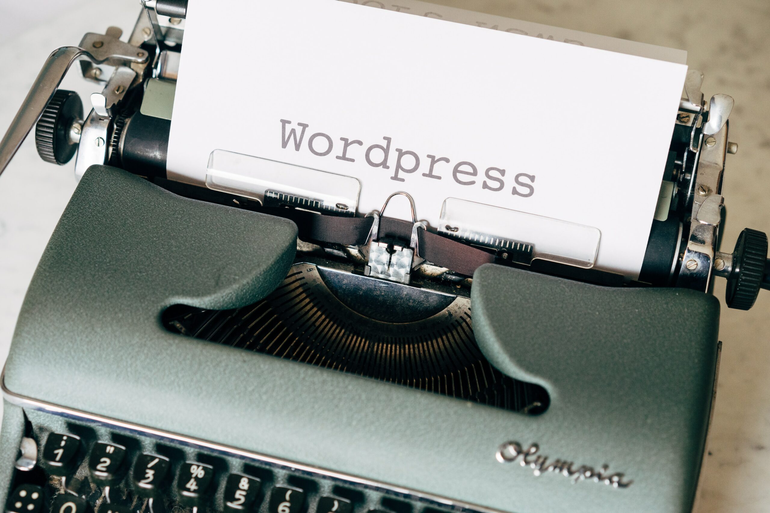 A typewriter with one sheet of paper in it. The paper reads: Wordpress.